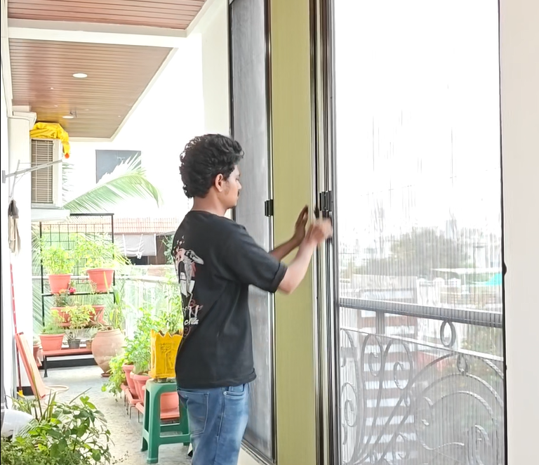 Opening pleated mosquito screen door on modern balcony